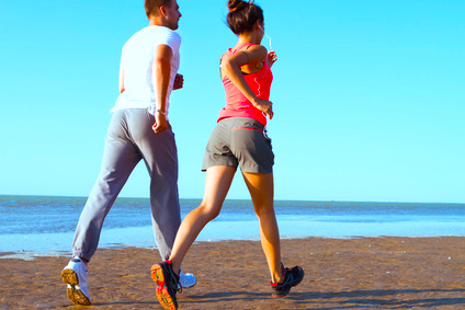 Young couple running together beside the water at the beach. Man and woman training outdoors.